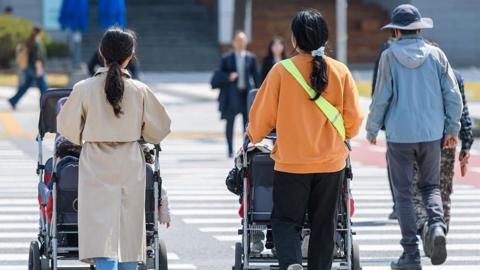 People seen with multi-seat strollers with babies in Gwanghwamun Square in the heart of Seoul. Gwanghwamun Square in front of Gwanghwamun, the main gate of Gyeongbokgung Palace, a tourist attraction in Seoul, is a public square in central Seoul.