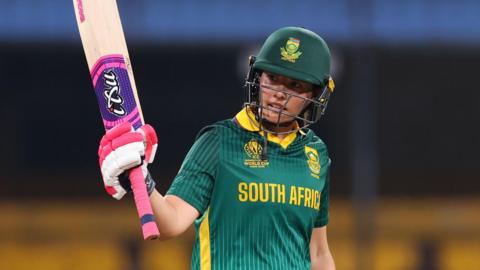 South Africa batter Sune Luus raises her bat after hitting fifty