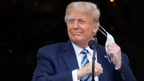 U.S. President Donald Trump takes off his face mask as he comes out on a White House balcony to speak to supporters gathered on the South Lawn for a campaign rally that the White House is calling a "peaceful protest" in Washington, U.S., October 10, 2020.