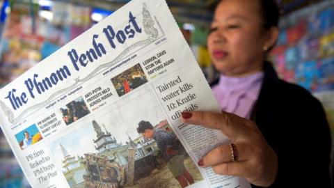 A Cambodian vendor reads the Phnom Penh Post newspaper at her newsstand in Phnom Penh, May 2018