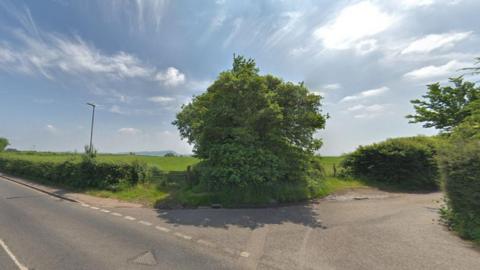 The planned entry to the new development on Gypsy Lane. It is a country lane by a field.