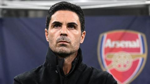 Arsenal manager Mikel Arteta looking pensive with the club badge in the background