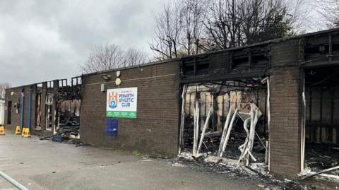 Llun o adeilad y clwb wedi ei difrodi gan dân