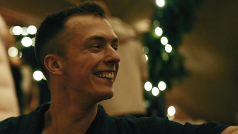 Close up image of smiling young man with sparkly lights behind him