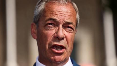 This photo has a close-up of Nigel Farage's face as he is talking to an audience 