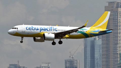 A Cebu Pacific Airbus A320 passenger aircraft prepares to land at the Ninoy Aquino International airport as the skyline of the Makati business centre is seen from Taguig City, suburban Manila.