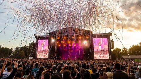 Crowds watch a performance on the main stage at All Points East festival in Victoria Park as streamers are released above the audience.