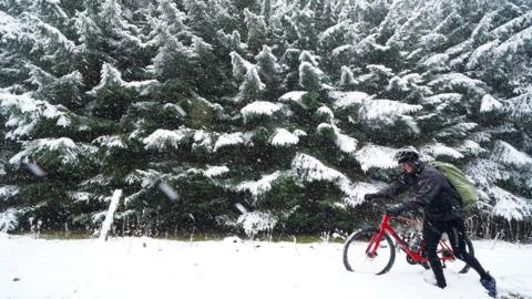 Man pushes bike through snow