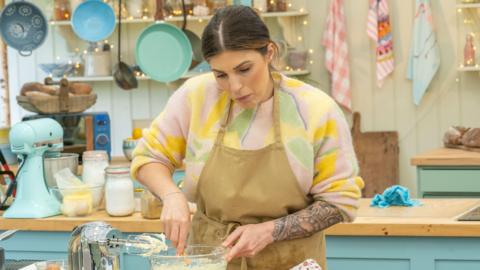 Bake Off contestant Georgie Grasso pictured in the Great British Bake Off kitchen mixing a batter.