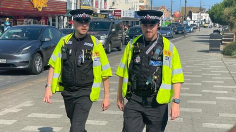 Two police officers walk towards the camera in Southend