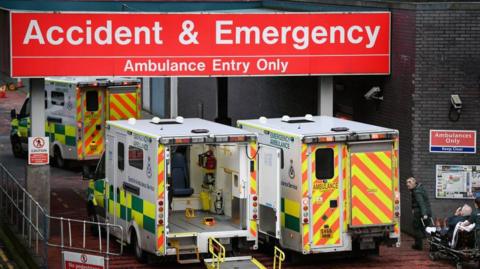 Ambulances outside a hospital with a red sign saying Accident & Emergency