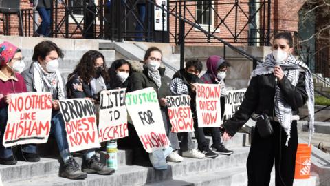 Students part of the hunger strike sit on the steps of Brown's Student Centre holding signs that say 'Brown Divest Now'