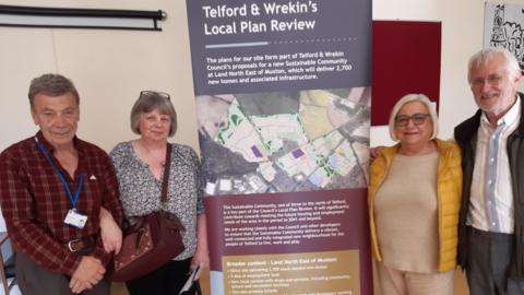 Two men and two women are standing either side of a large banner that is titled "Telford and Wrekin's local plan review", with an aerial picture of a piece of land earmarked for development. There is subsequent text below