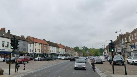 Google Streetview of Yarm town centre. A number of vehicles are travelling along a main road near traffic lights. Other vehicles are parked to either side of the road.