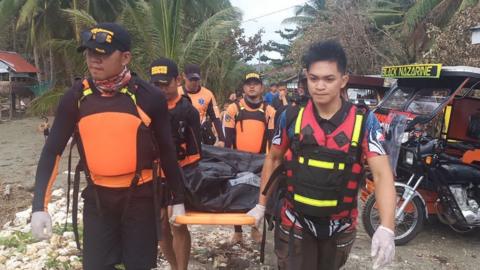 Rescuers carry a body body, believed to be one of several fishermen who went missing at the height of Typhoon Phanfone