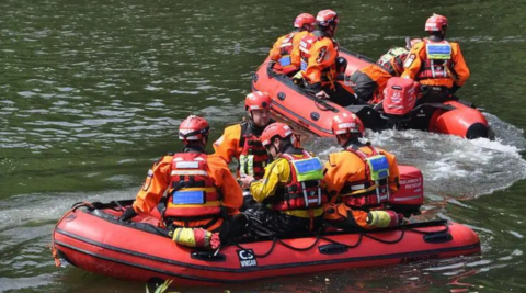 Two red dingies, crewed by people in orange life jackets and red helmets