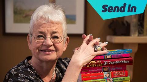 Dame Jacqueline Wilson looks at the camera, holding onto a pile of her books.