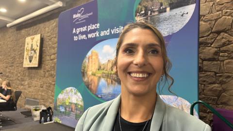 A woman with long dark hair smiles at the camera
