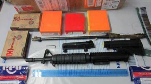 A police image of an assault rifle and handguns on a desk alongside boxes of bullets