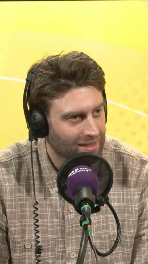 Jordan Clark speaks into a microphone and wears headphones.