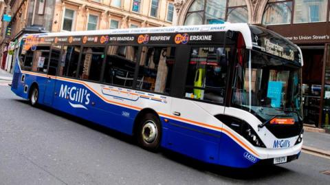 A blue and white bus driving down the street