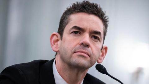 Isaacman in dark suit behind microphone