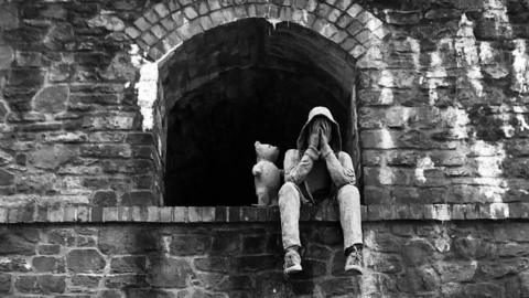 Man sitting on a ledge next to a bear