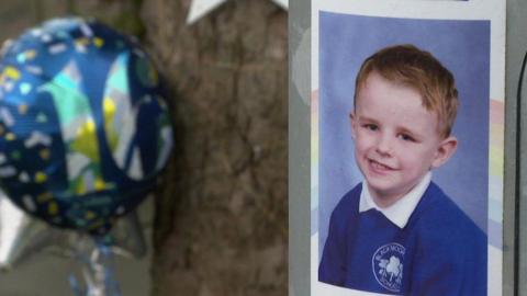 A flyer fixed to a lamp-post containing a photo of smiling six-year-old Bobby Colleran in his blue school uniform. In the background is a blue balloon with the number 16 on it next to a tree.