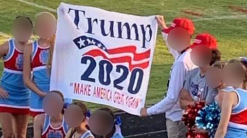 Cheerleaders pose with a President Trump banner