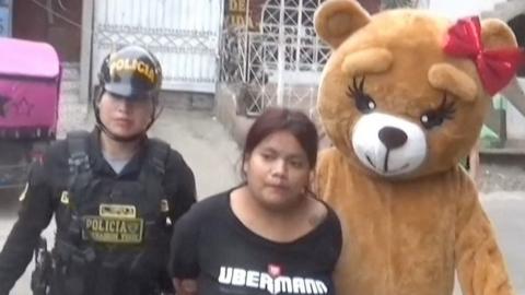 Woman being escorted by two police officers, one dressed as a teddy bear.