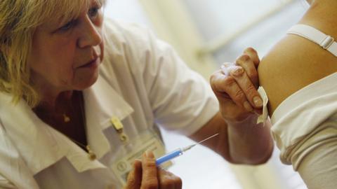 nurse adminsters flu jab to woman