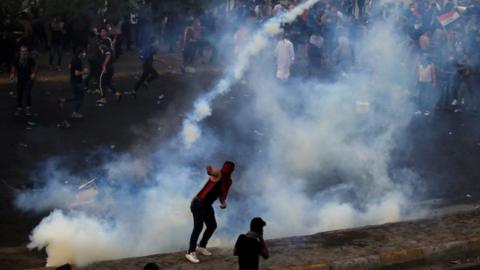 Demonstrator throws a tear gas canister in Baghdad