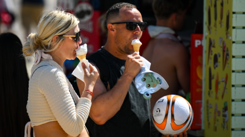 A man and a woman eating ice cream cones in the sunshine