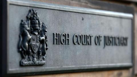 Sign outside building which says HIGH COURT OF JUSTICIARY in bold letters.