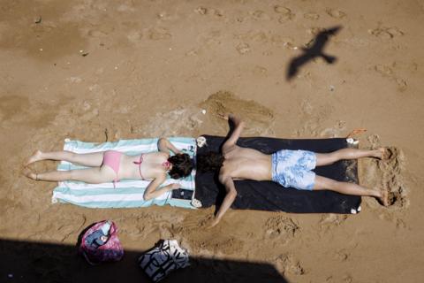 People lying with their backs to the sun on a beach