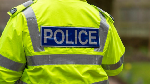 The back of a police officer wearing a yellow high vis jacket