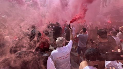 A large cloud of red smoke is seen over West Street in Bristol as Bristol City fans gather for their Flag Day rally. Many of them are holding up smoke flares which are creating the cloud