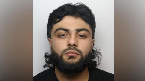 Luqman Khan, an Asian male with long black hair and a black beard.