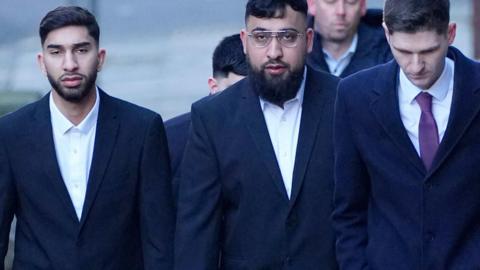 Mohammed Fahir Amaaz (left) and Muhammed Amaad (centre) arrive at Liverpool Magistrates' Court wearing black suits, joined by their solicitor