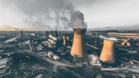 Aerial view of Scunthorpe steelworks showing a number of industrial buildings and steam rising from large chimneys