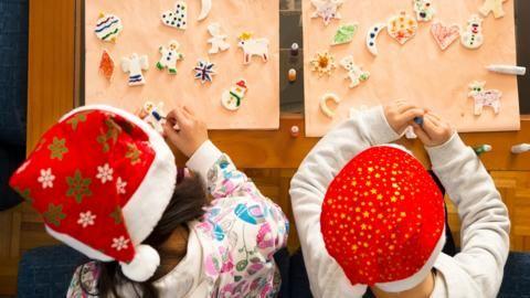 Children doing crafts with Santa hats on.