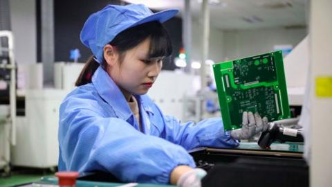 This photo taken on December 23, 2020 shows an employee working on photovoltaic products at the workshop of a renewable energy company in Tonglu, in eastern China's Zhejiang province.