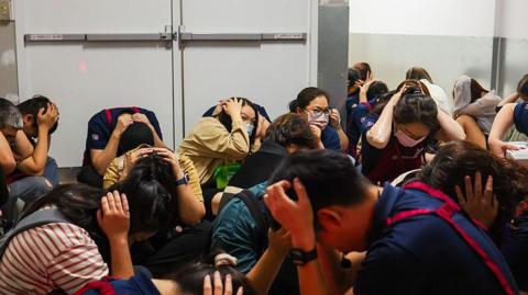 Shoppers and supermarket employees crouch and cover their heads and ears in an underground shelter during an air raid evacuation rehearsal in Taipei