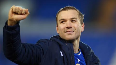 Goalscorer Michael Cheek raises his right fist to celebrate Bromley's victory at Tranmere after the game wearing a navy coat over his kit