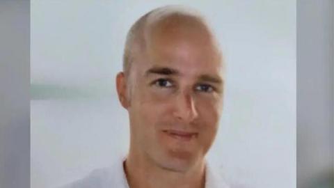 A head and shoulders shot of a bald man who is smiling. 