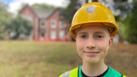 Smiling teenage boy in a green top and yellow safety hat