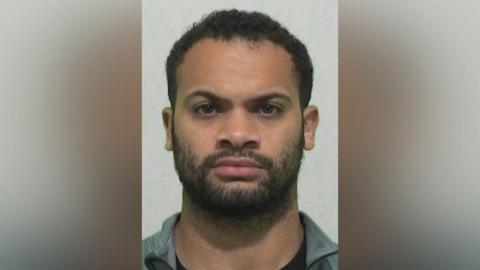 Mugshot of Malachi Jamieson. He has a short black beard and short black curly hair.