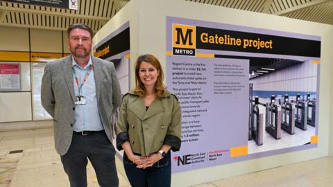 Paul Welford, Nexus Major Projects Director, and North East Mayor Kim McGuinness at Regent Centre Metro station. Behind them is a poster about the new gates.