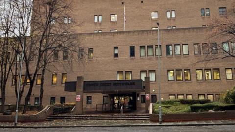A picture of the front of Southwark Crown Court. It is a large brick building with many windows and an entrance at the front.