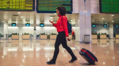 Woman walks with suitcase in an airport